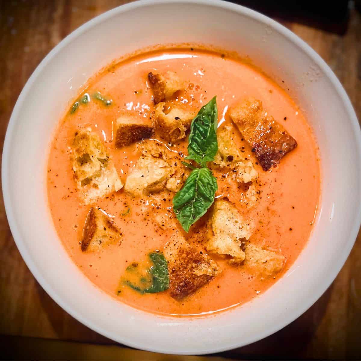 Birds eye view of tomato basil soup in a white bowl.