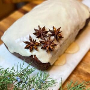 Glazed citrus orange cardamom cake sitting on a white cutting board.