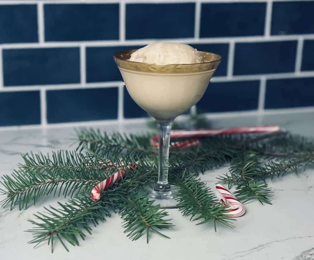 Snow Day Holiday Cocktail in a gold rimmed glass with snowball ice.