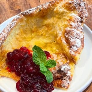 Dutch baby with cranberry compote on a white plate.