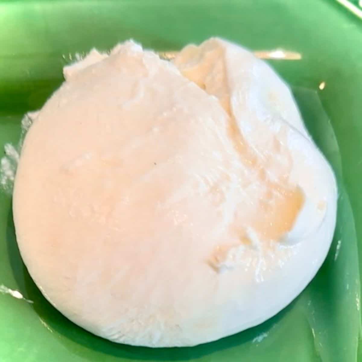 Burrata cheese on a green platter.