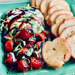 Burrata Crostini appetizer sitting on a green plate.