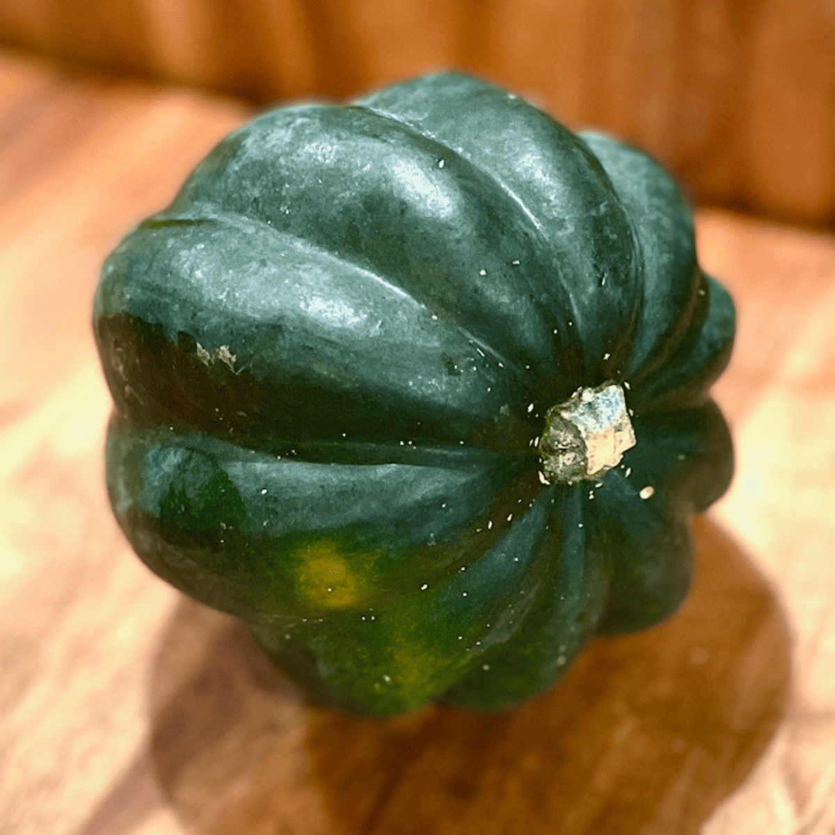 Dark green acorn squash sitting on a wooden counter.