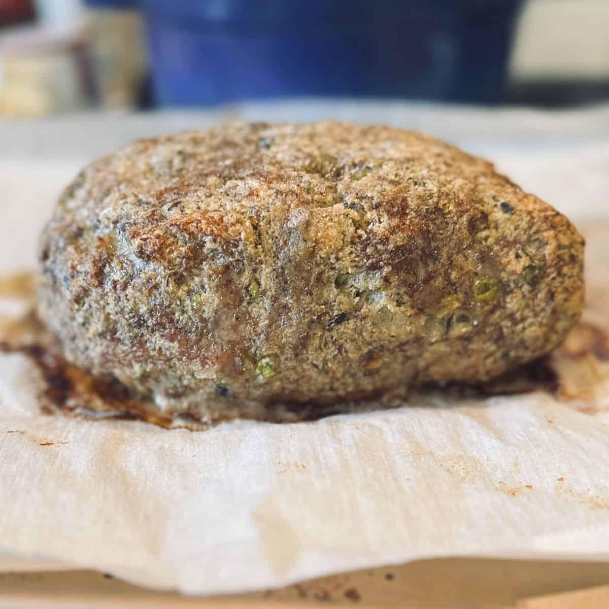 Cooked meatloaf without the glaze, sitting on a piece of parchment paper.