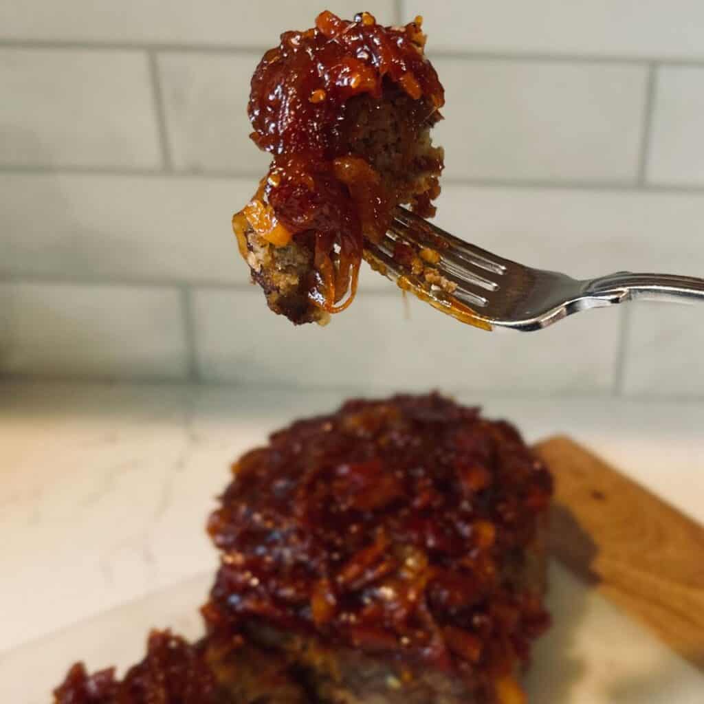 Meatloaf with tomato onion jam on a fork.