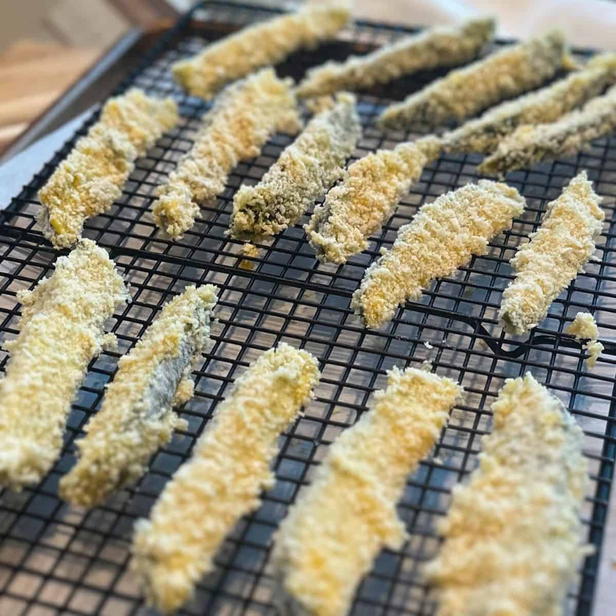 Breaded pickles on a baking rack.
