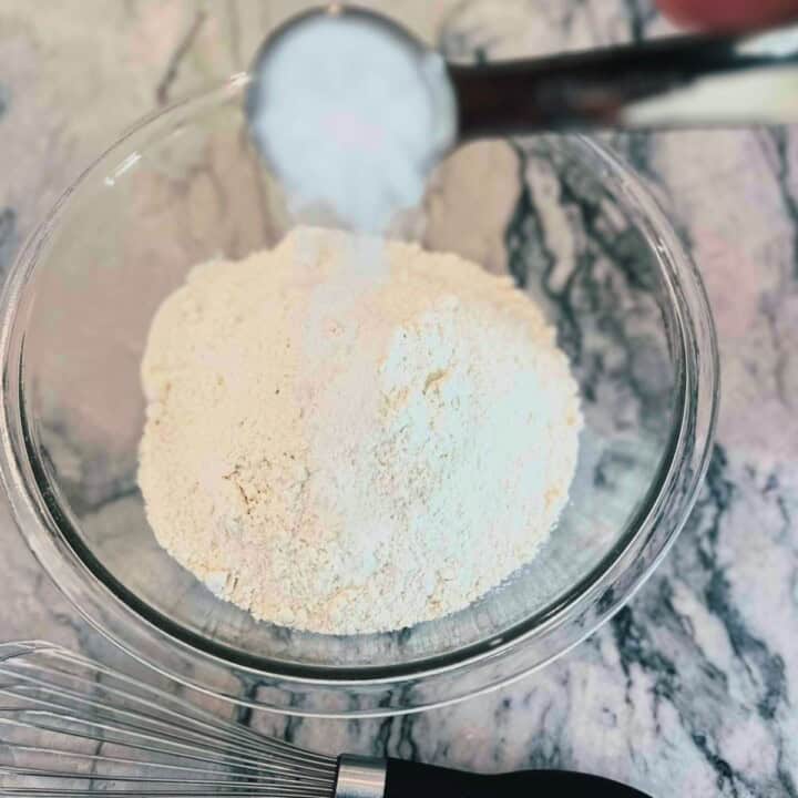 Salt being poured into a bowl of flour.
