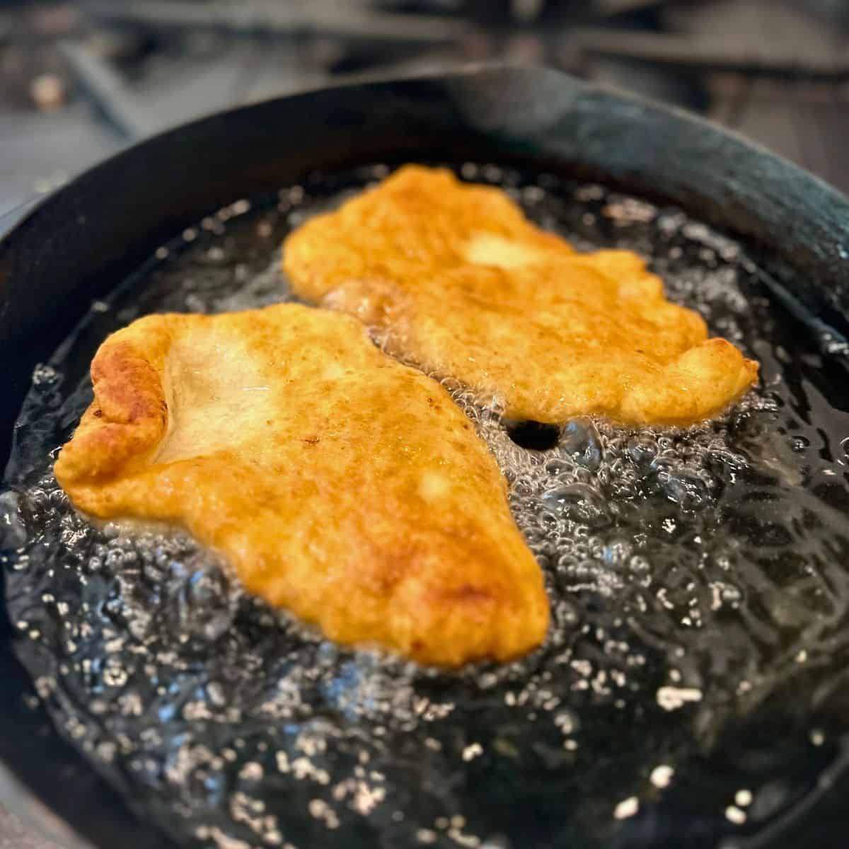 Fry bread frying in a cast iron pan.