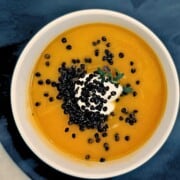 Bowl of butternut squash soup with black lentils in a white bowl.