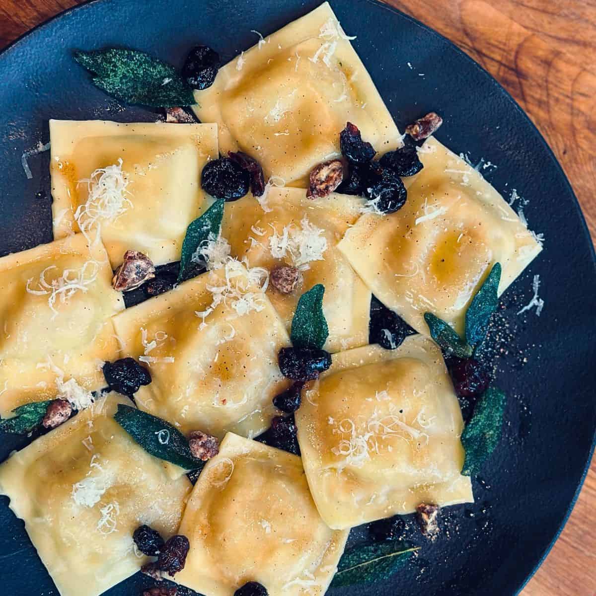 Butternut squash ravioli on a black plate.