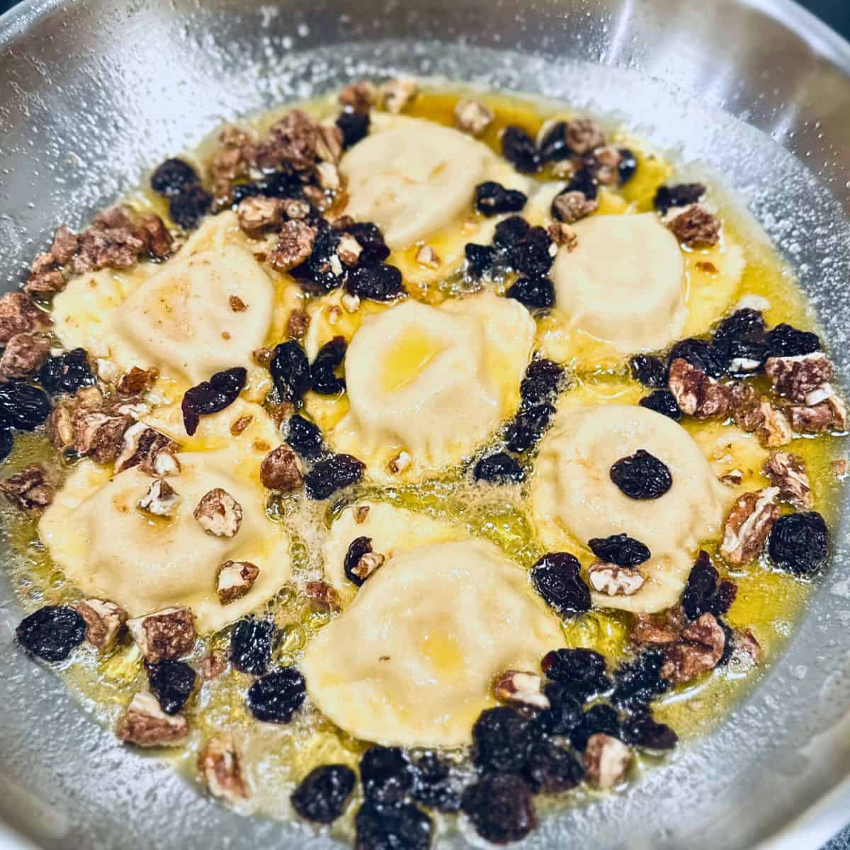 Ravioli with brown butter sauce in a skillet.