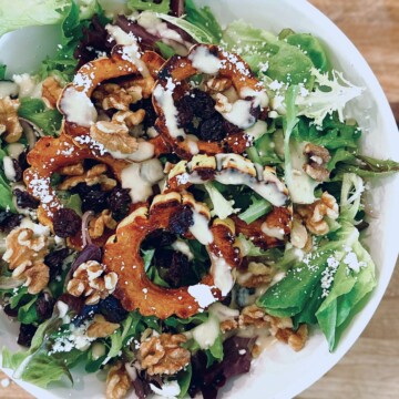 Delicata squash salad with maple dijon dressing in a white bowl.