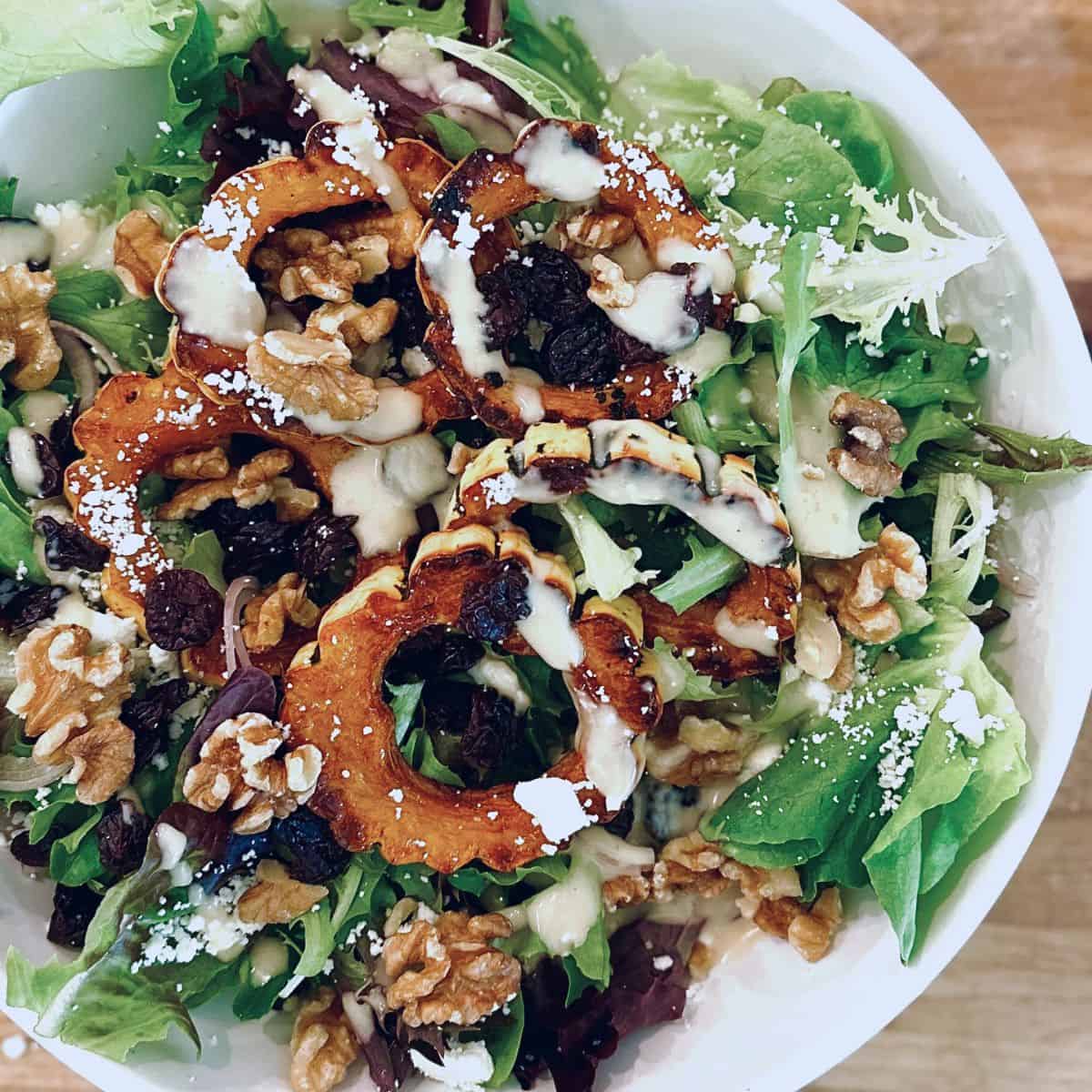 Delicata squash salad with maple dijon dressing in a white bowl.