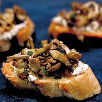 Wild mushroom crostini on a black plate.