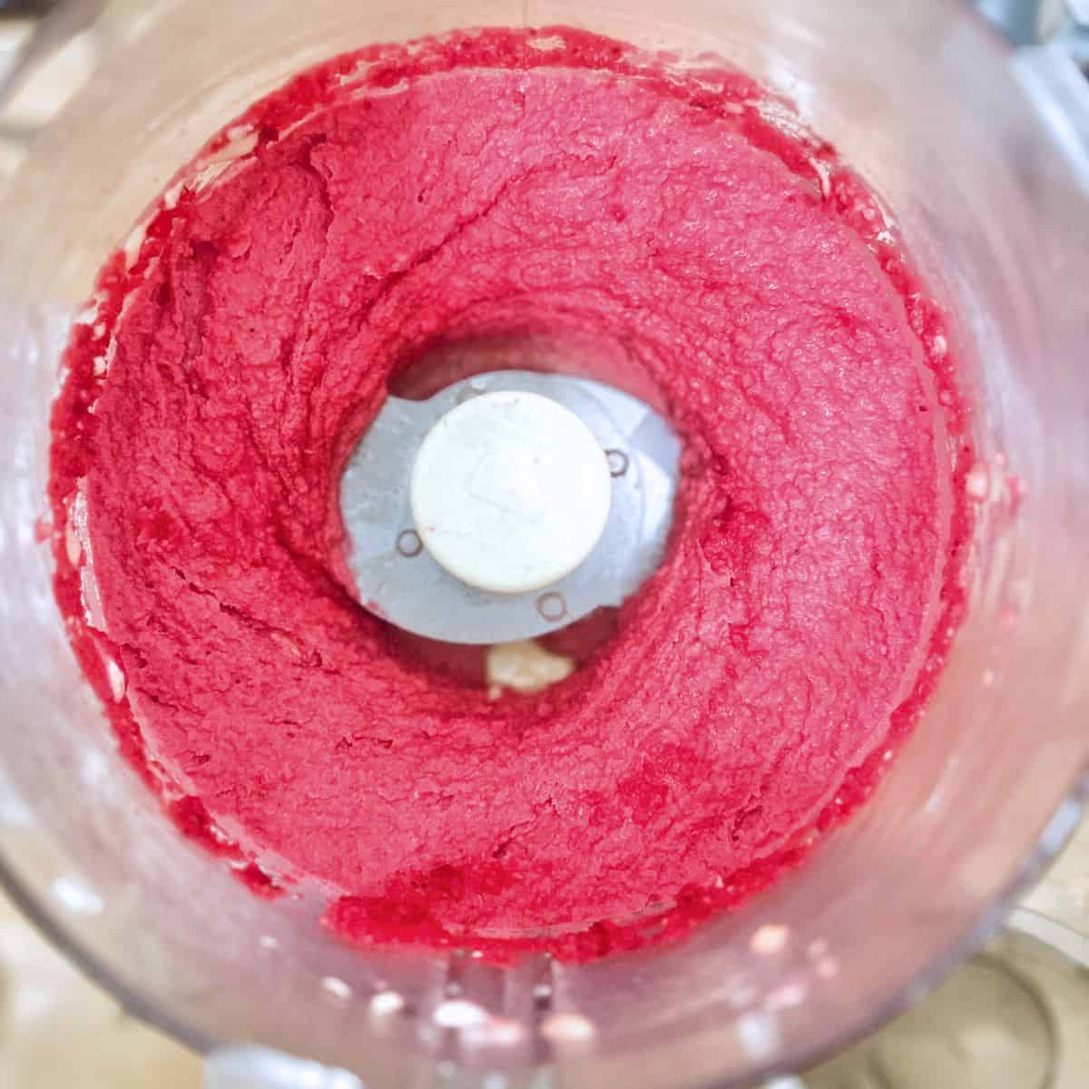 Birdseye view of beet hummus in a food processor.