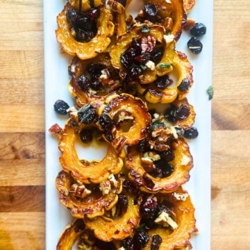 Roasted delicata squash with sage brown butter on a white platter.